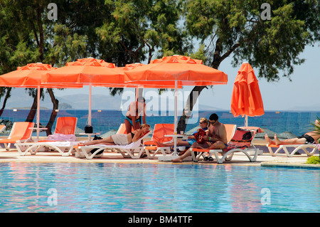 Zwei Paare zu entspannen, um einen Hotel-Swimmingpool im Badeort von Turgutreis in der Nähe von Bodrum, Türkei Stockfoto