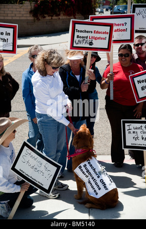 Unterstützt von einem Hund und tragen Schilder, protestieren Lehrer Schulstreik über vorgeschlagene Lohnkürzungen in San Juan Capistrano, Kalifornien. Stockfoto