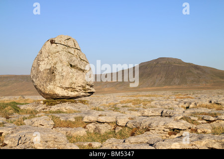 Ein Findling steht auf Kalkstein Pflaster mit Ingleborough in der Ferne, Ribblesdale, Yorkshire Dales National Park Stockfoto