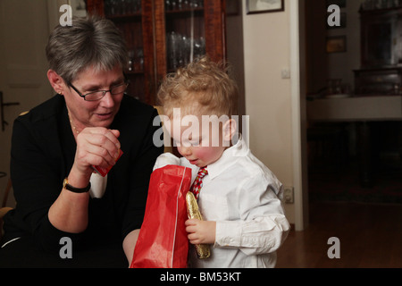 Zwei Jahre altes Kleinkind sieht und greift in einen Beutel mit Süßigkeiten zu einem Familienfest-Modell veröffentlicht Stockfoto