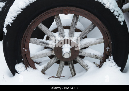 Schnee bedeckt eine verlassene Traktor Holzwagen Radnabe aus einem alten Fahrzeug auf einer Farm in Finnland Stockfoto