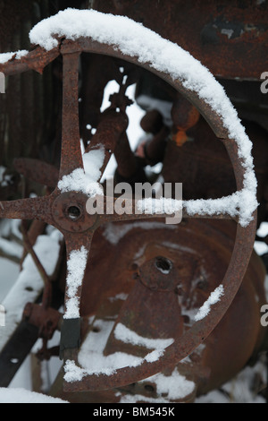 Schnee bedeckt einen Lenkrad auf einen rostigen verlassenen antiken Ford Traktor auf einer Farm in Finnland Stockfoto