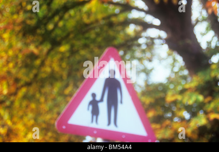 Impressionistische dreieckigen Roadsign mit Herbstlaub hinter Warnung, die Erwachsene oder Kinder auf der Straße zu Fuß werden kann Stockfoto