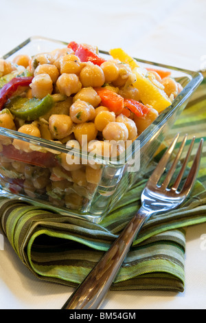 Vegane Salat aus Kichererbsen und mit Frühlingszwiebeln, Petersilie, Karotten, rote und gelbe Paprika gemischt. Garniert mit dressing Stockfoto