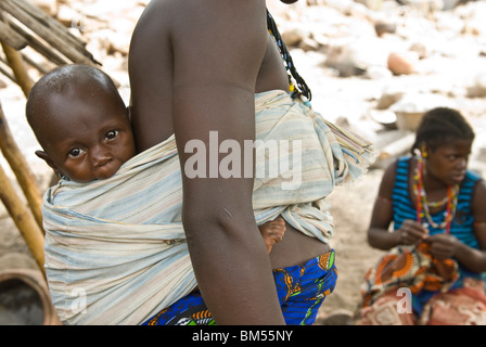 Afrikanische Bedik Frau mit einem Kind dabei Hausarbeit, Iwol Dorf, Bassari-Land, Senegal, Afrika. Stockfoto