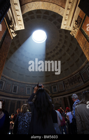 Pantheon Rom Italien. Frau Tourist fotografierte Denkmal innen, Sunbeam wahr die Öffnung an der Oberseite der Kuppel. Stockfoto