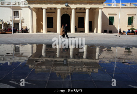 Vorbei an ein paar einen Brunnen in einem Quadrat. Dahinter befindet sich ein sechs Säulen-Portikus. Es gibt Spiegelungen im Wasser. Stockfoto