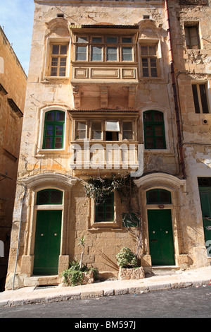 Ein traditionelles Haus in Valletta, Malta, zeigt die typischen geschlossenen Holzbalkonen, gewölbte Türen und Fenster und auf einem Hügel. Stockfoto