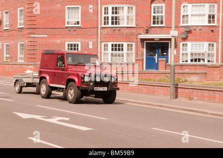 Rotes Land Rover Defender 90, ziehen eines einachsigen Anhängers durch Norwich Stockfoto