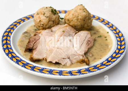 Suckling Schweinebraten (Jungschweinesbraten) serviert mit Knödel und Pilzsauce in Bayern, Deutschland. Stockfoto