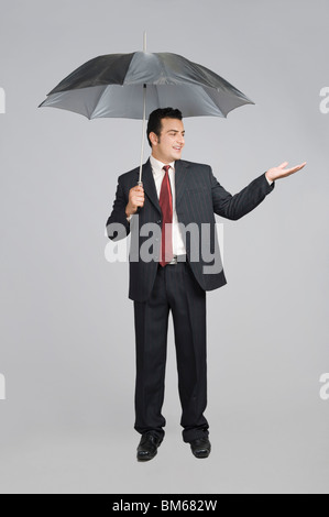Kaufmann unter einem Regenschirm Regen gesucht Stockfoto