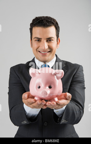 Porträt eines Geschäftsmannes hält ein Sparschwein Stockfoto