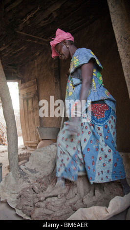 Eine Frau mischt sich kleine Stücke von gebranntem Ton (Grog) mit Tonkörper durch Stanzen drauf in der Töpferei Dorf von Kalabougou in Mali. Stockfoto