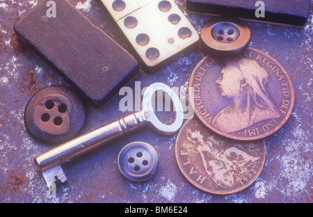 Kleine silberne Schlüssel mit Domino Stücke drei männliche Tasten und zwei alte britische Münzen auf Rosten Metalltablett liegen Stockfoto