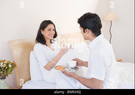 Mann seine Frau auf dem Bett und Tee verleiht Stockfoto