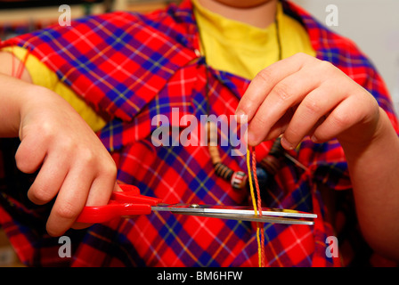Junge Grundschüler schneiden farbige Wolle mit einer Schere in & Designtechnologie Lektion Grayshott, Haslemere, Großbritannien.