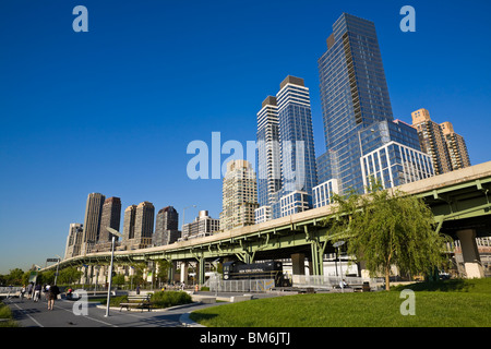 Menschen genießen einen wunderschönen sonnigen Tag zu Fuß durch den Park entlang des Hudson River vor dem Hintergrund der Gebäude. Stockfoto