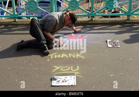 Ein Pflaster-Streetart-Künstler mit farbigen Kreiden um eine Kreidezeichnung in Brighton zu erstellen. Stockfoto