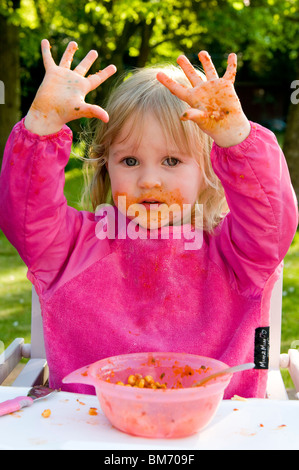 KLEINKIND MÄDCHEN, GENIEßT IMMER CHAOTISCH WÄHREND ESSEN PASTA IN TOMATENSAUCE Stockfoto