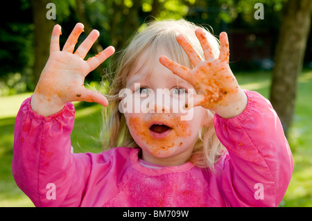 KLEINKIND MÄDCHEN, GENIEßT IMMER CHAOTISCH WÄHREND ESSEN PASTA IN TOMATENSAUCE Stockfoto