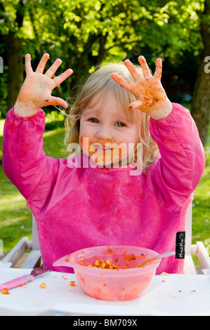 KLEINKIND MÄDCHEN, GENIEßT IMMER CHAOTISCH WÄHREND ESSEN PASTA IN TOMATENSAUCE Stockfoto