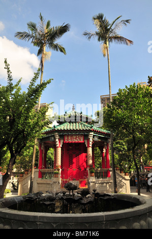 Blick durch ein Lotus-Brunnen, Palmen über den roten Türen von Yue Hing Buddha-Schrein, Wong-Tai-Sin-Tempel, Hong Kong Stockfoto