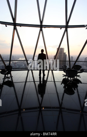 Ein Geschäftsmann Stand mit seiner Aktentasche am oberen Rand der Wolkenkratzer Gherkin in der City of London, U.K Stockfoto