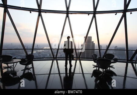 Ein Geschäftsmann Stand mit seiner Aktentasche am oberen Rand der Wolkenkratzer Gherkin in der City of London, U.K Stockfoto