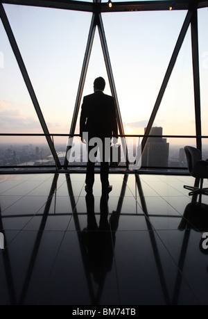 Ein Geschäftsmann Stand mit seiner Aktentasche am oberen Rand der Wolkenkratzer Gherkin in der City of London, U.K Stockfoto