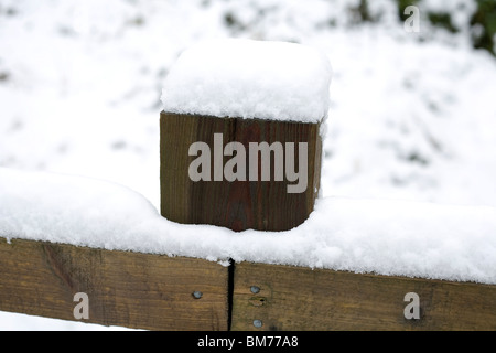 Holzzaun und Zaunpfahl gekrönt von Schnee neben einem Wanderweg führt auf den Sanddünen bei Newton, Porthcawl Stockfoto