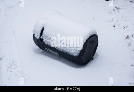 Eine schwarze Mülltonne liegt in seiner Seite im Schnee an einem ungewöhnlich kalten Wintertag an der Glamorgan Küste Stockfoto