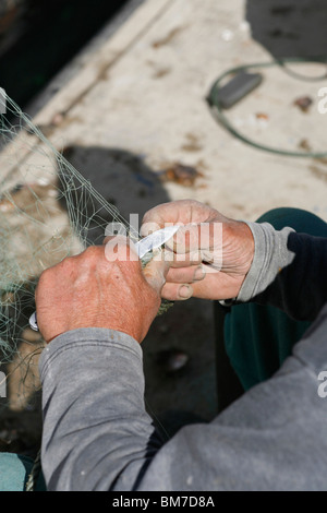 Ein Fischer schneiden ein Fischernetz, Fokus auf Händen Stockfoto