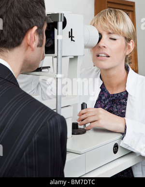 Ein Augenarzt mit einer Spaltlampe Biomicroscope um einen Patienten zu untersuchen Stockfoto