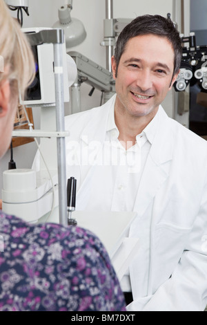 Ein Augenarzt mit einer Spaltlampe Biomicroscope um einen Patienten zu untersuchen Stockfoto