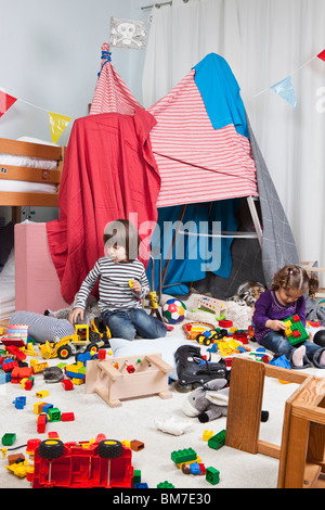 Ein kleiner Junge und ein Mädchen spielen in einem Schlafzimmer Stockfoto