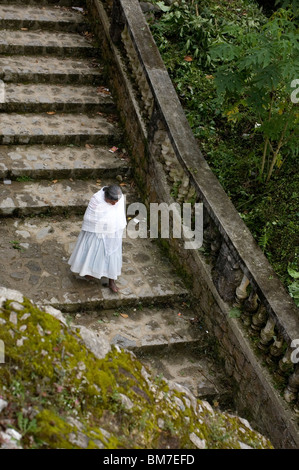 Eine indigene Frau Nahuatl steigt Treppen hinter Guadalupe Heiligtum Kirche, Cuetzalan, Mexiko. Stockfoto