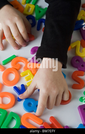 Ein Junge spielt mit Brief Magnete, Detail der Hände Stockfoto