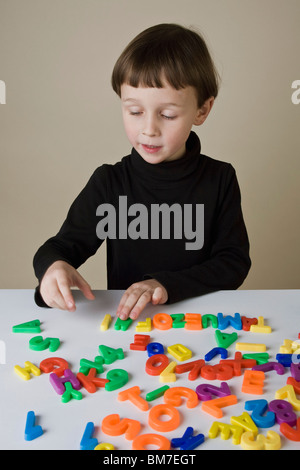 Ein Junge spielt mit Brief Magnete Stockfoto