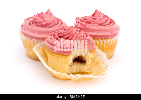 drei rosa Tasse Kuchen auf einem weißen Hintergrund mit einem Biss genommen Stockfoto