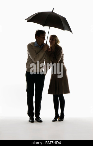 Ein Mann und eine Frau unter einem Regenschirm kauern Stockfoto