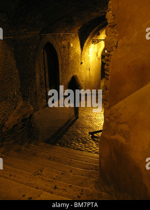 Person, die nachts in dunklen Gasse in Rom Italien Stockfoto