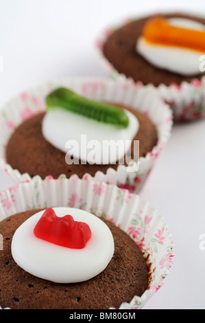 Hausgemachte Mini Schokoladen Cupcakes gekrönt mit Zuckerguss und wigglely Wurm Süßigkeiten. Stockfoto