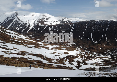 Blick über den Lairig Ghru gegenüber Ben Macdui in Cairngorm National Park Schottland Großbritannien als Mann Wanderungen den Hang hinauf. Stockfoto