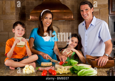 Eine attraktive glücklich und lächelnd Familie von Mutter, Vater, Sohn und Tochter machen gesunde Sandwiches in Küche zu Hause Stockfoto
