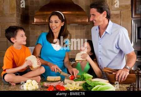 Eine attraktive glücklich und lächelnd Familie Mutter, Vater, Sohn und Tochter machen gesunde Sandwiches in einer Küche zu Hause Stockfoto