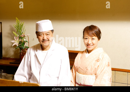 Portrait von einer Frau im Kimono und japanischen Chefkoch, lächelnd, Stadt Kyoto, Kyoto Prefecture, Japan Stockfoto