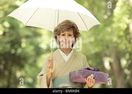 Portrait von reife Frau im Kimono holding Regenschirm und Geschenk, Stadt Kyoto, Kyoto Prefecture, Japan Stockfoto