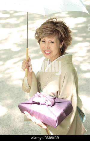 Portrait von reife Frau im Kimono holding Regenschirm und Geschenk, Stadt Kyoto, Kyoto Prefecture, Japan Stockfoto