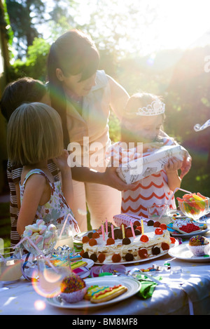 Mädchen Eröffnung Geschenk bei Outdoor-Geburtstagsparty Stockfoto