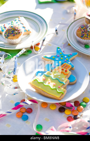 Eistee, Cookies, Muffins auf Tisch geschmückt mit Luftschlangen und Süßigkeiten Stockfoto